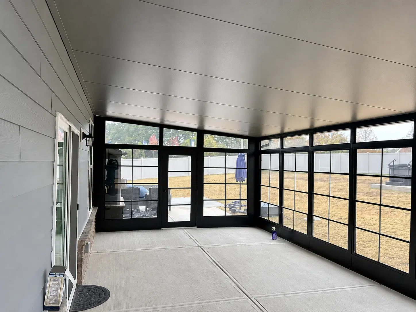 Interior view of a black frame sunroom model 200 enclosure with large screened windows, concrete floor, and backyard views for Myrtle Beach outdoor living.